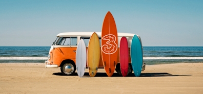 En masse surfbræt foran en bil på en strand