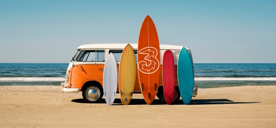 En masse surfbræt foran en bil på en strand